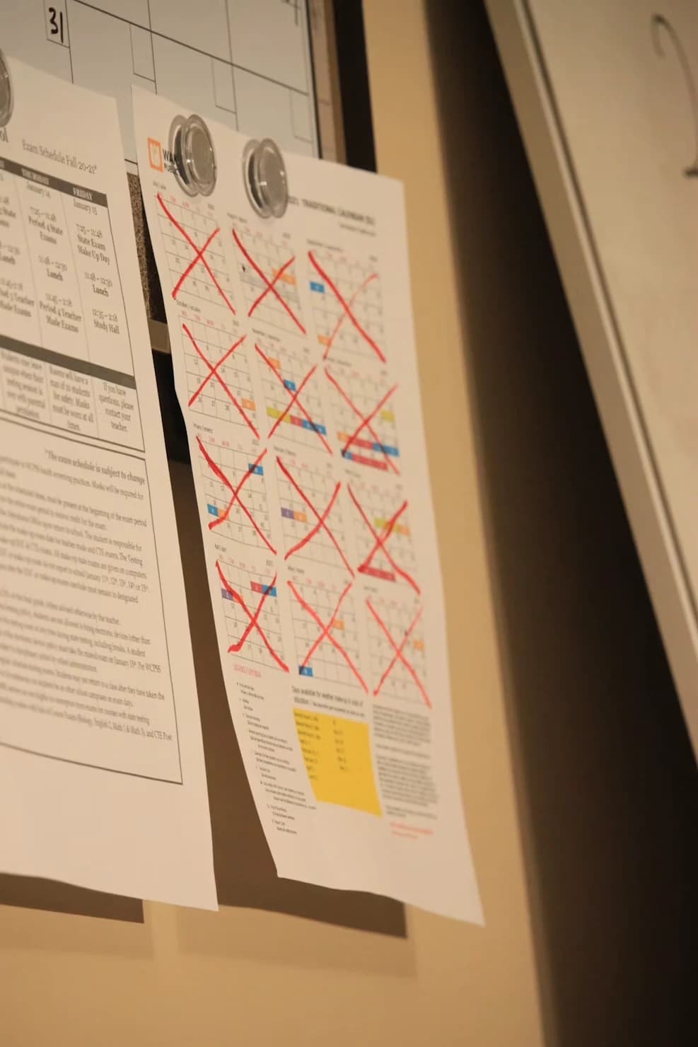 A year calendar pinned to a wall with whole months crossed off in red marker
